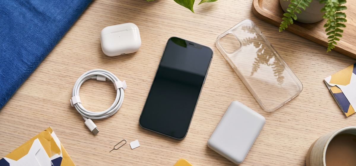 Smartphone, earbuds, charger and case on a desk