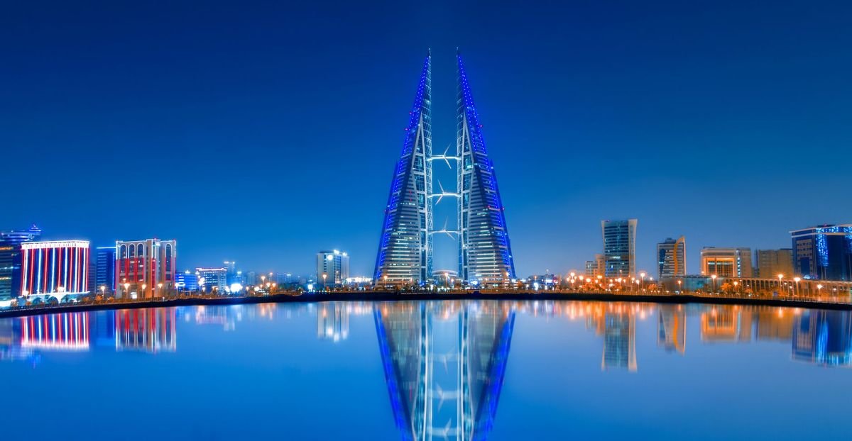 Bahrain World Trade Center and the Manama skyline reflected in the water at dusk