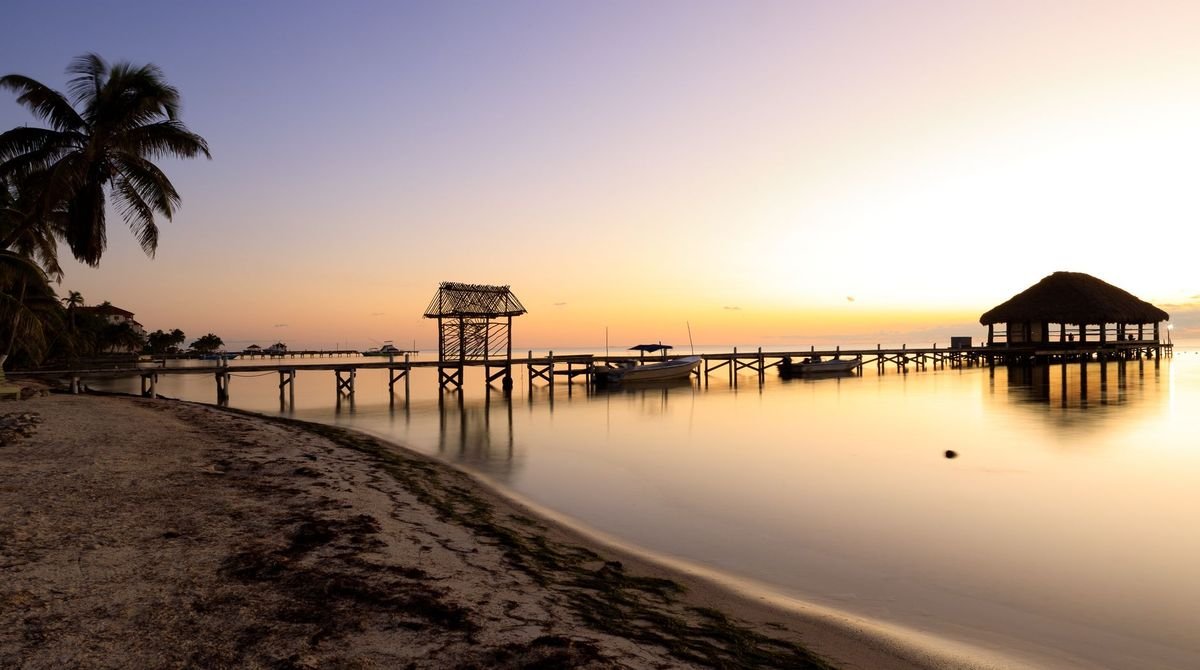 Wooden jetty over calm water at sunset in Belize