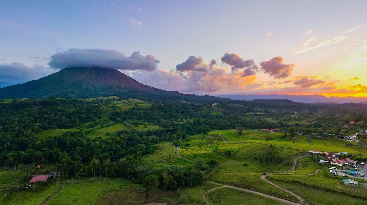 Arenal Volcano above green farmland at sunset, Costa Rica