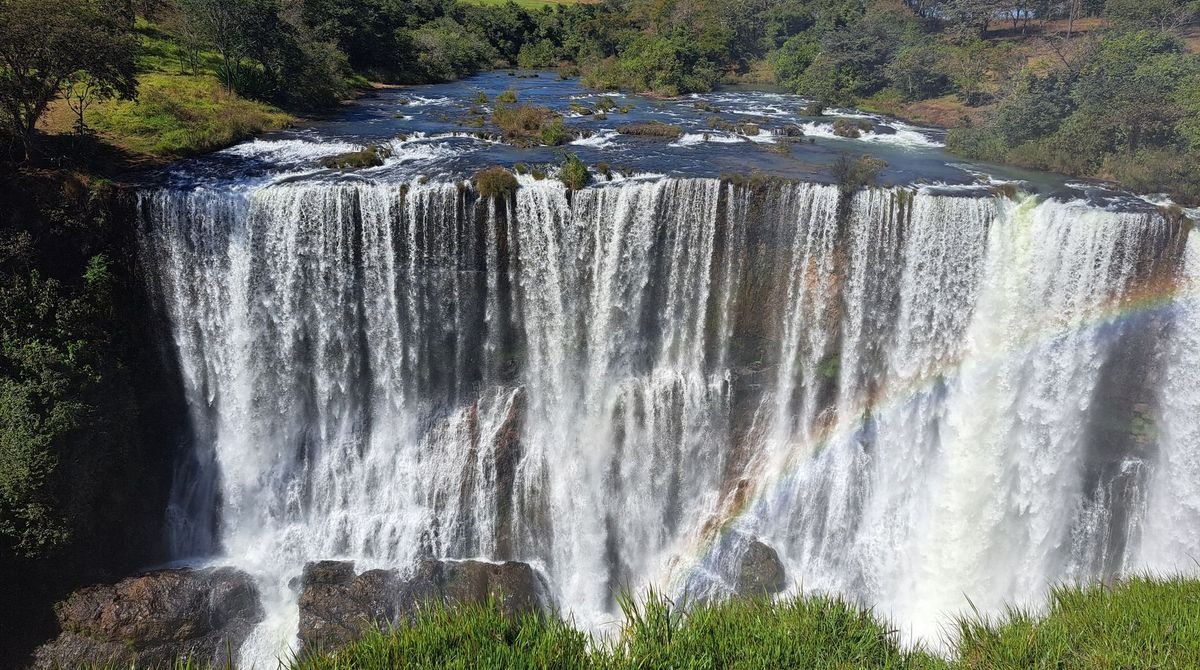 Wide waterfall surrounded by green bush in West Africa