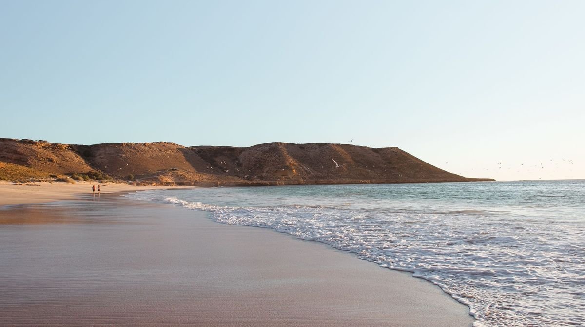 Wide sandy beach below green hills on the West African coast